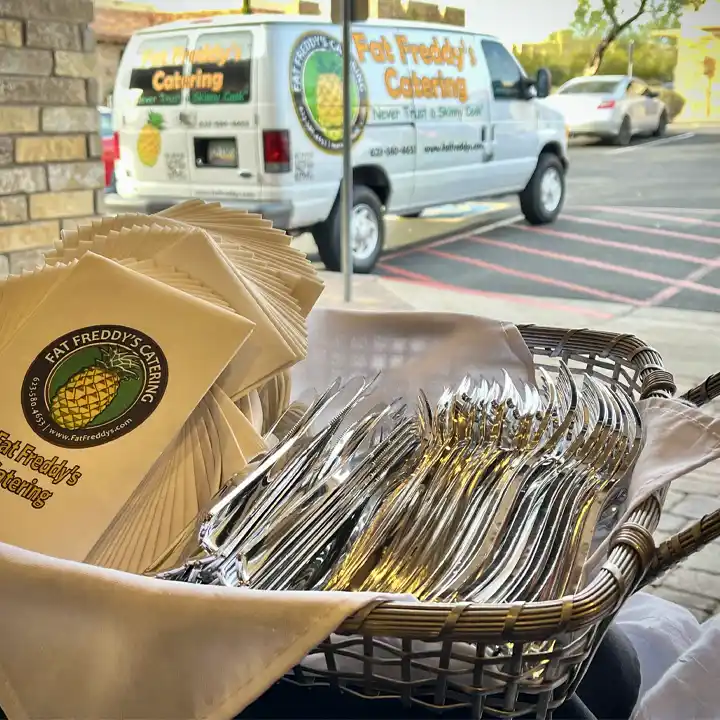 Basket of flatware with Fat Freddy's napkins and a van